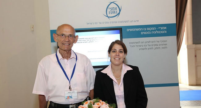 שמעון בוקשפן, מזכיר אמצ"י, ארגון משתמשי ציוד יבמ בישראל, ולצידו דיילת, בעמדת הארגון בכנס