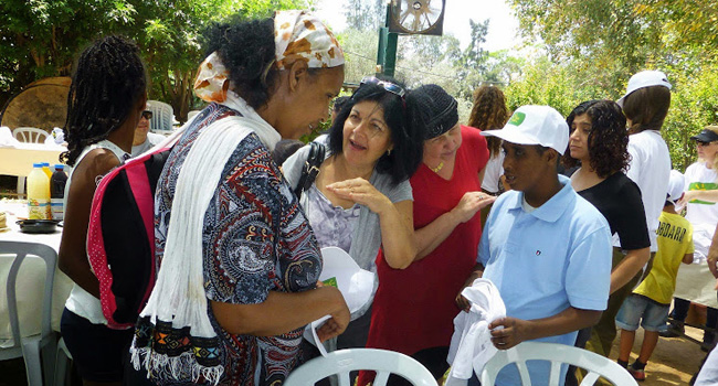 ד"ר אילנה גלייטמן, באדום, מנהלת השירות לעיוור במשרד הרווחה, בשיחה עם אחד החוגגים. שיתוף הפעולה המושלם בין פרויקט "גשר של אור" לשירות לעיוור, לאורך כל השנה, הוא המפתח להצלחת הפרויקט. תרומתה של אילנה בהקשר זה היא אינסופית