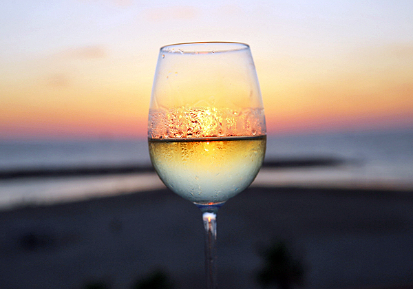 המראה הקסום של כוס יין לבן על רקע השקיעה במלון דן אכדיה בהרצליה. צילום: ניב קנטור